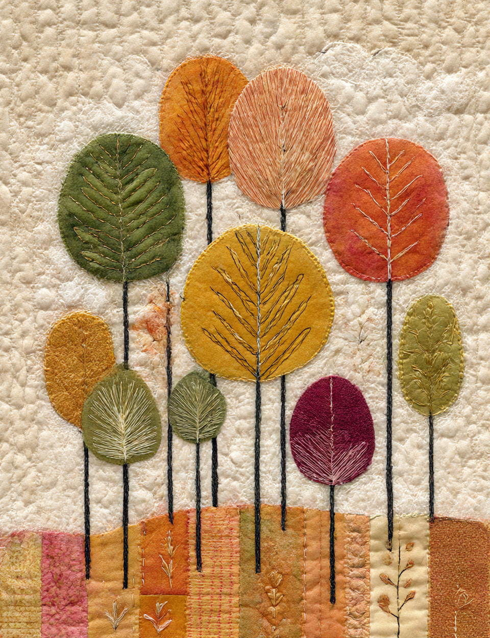 Textile art with embroidered leaves in autumn colors on a textured fabric background